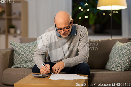 Image of senior man with bills and calculator at home