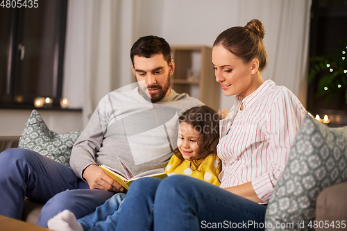 Image of happy family reading book at home at night