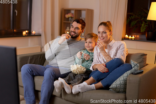 Image of happy family with popcorn watching tv at home