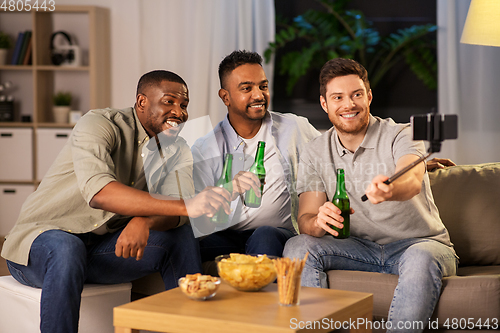 Image of male friends with smartphone taking selfie at home