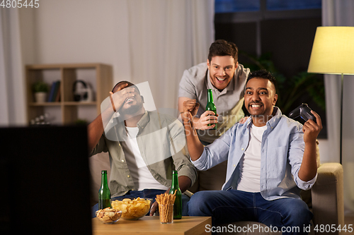 Image of happy friends playing video games at home at night