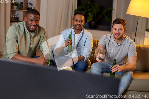 Image of happy male friends with beer watching tv at home