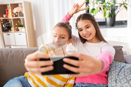 Image of happy girls taking selfie with smartphone at home