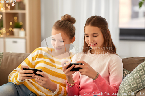 Image of happy teenage girls with smartphones at home