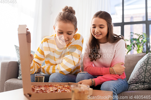 Image of happy teenage girls eating takeaway pizza at home