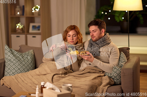 Image of sick young couple drinking tea with lemon at home