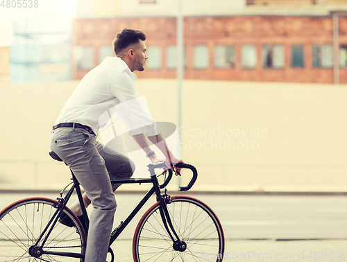 Image of man with headphones riding bicycle on city street