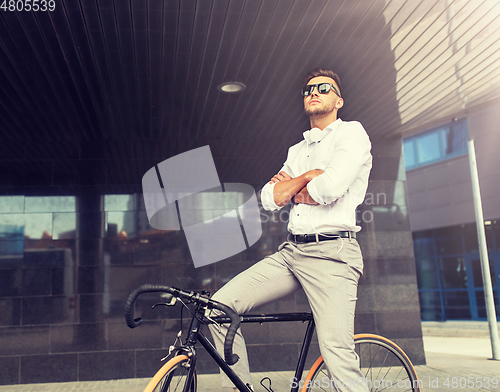 Image of man with bicycle and headphones on city street