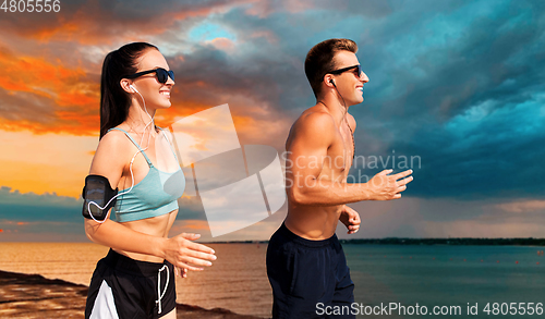 Image of couple with phones and arm bands running on beach