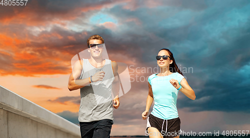Image of couple in sports clothes running outdoors