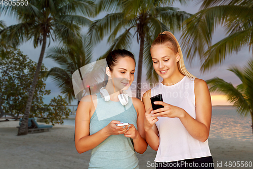 Image of women or female friends with smartphones on beach