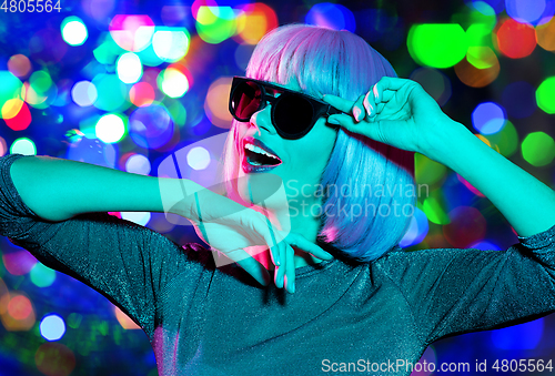 Image of happy woman in pink wig and sunglasses dancing