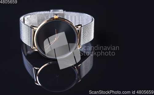 Image of Wrist watch with metal strap for women on black background
