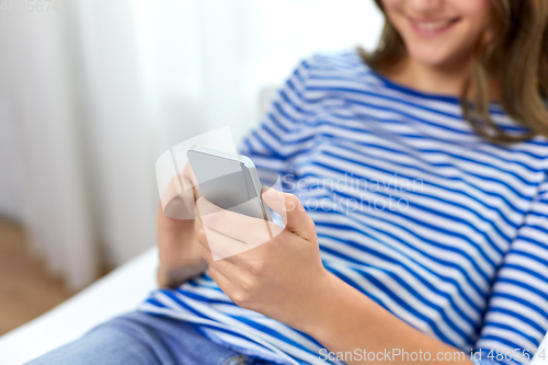 Image of smiling teenage girl using smartphone at home