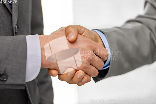 Image of close up of businessmen making handshake at office