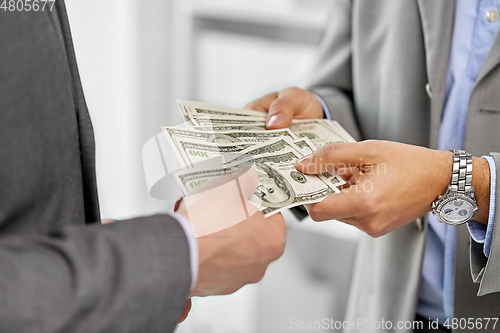 Image of close up of businessmen's hands holding money