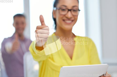 Image of happy young woman with tablet pc showing thumbs up