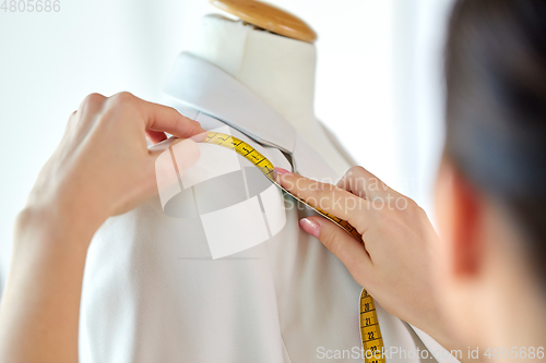 Image of fashion designer measures jacket with tape measure