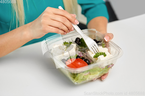 Image of hands of woman eating take out food from container