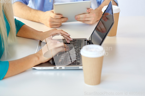 Image of woman typing on laptop and coffee cups on table