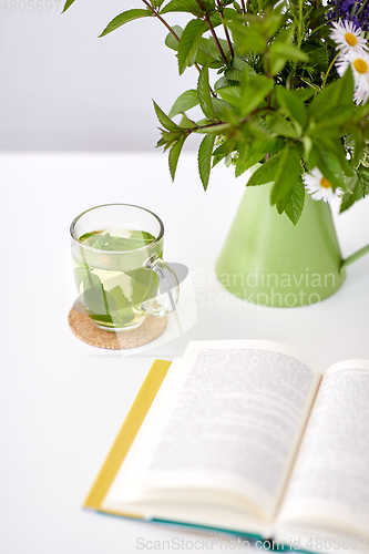 Image of herbal tea, book and flowers in jug on table