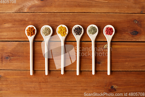 Image of spoons with different spices on wooden table