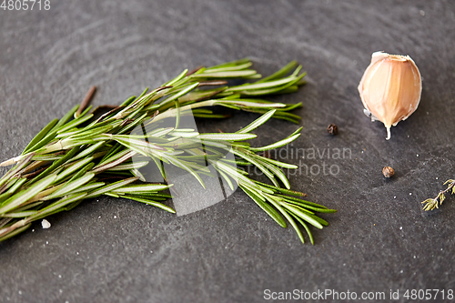 Image of rosemary, garlic and black pepper on stone surface