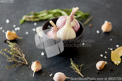 Image of garlic in bowl and rosemary on stone surface