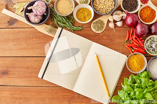 Image of notebook with pencil among spices on wooden table