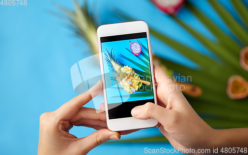Image of hands taking photo of exotic fruits on smartphone