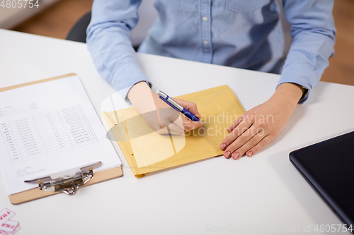 Image of woman writing on parcel envelope at post office