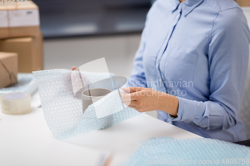 Image of woman packing mug to parcel box at post office