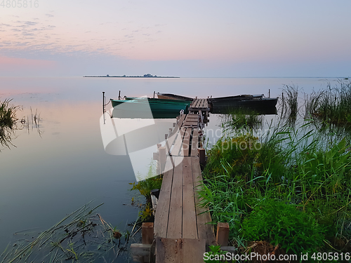 Image of Dawn begins. Wooden Pier for Boats on the Lake Shore