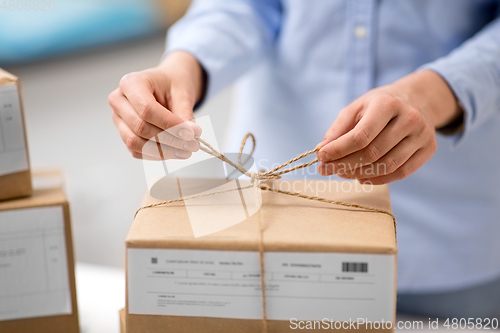 Image of woman packing parcel and tying rope at post office