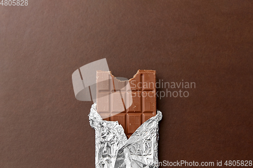 Image of chocolate bar in foil wrapper on brown background