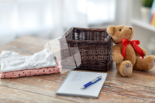 Image of baby clothes, teddy bear, toy blocks and notebook