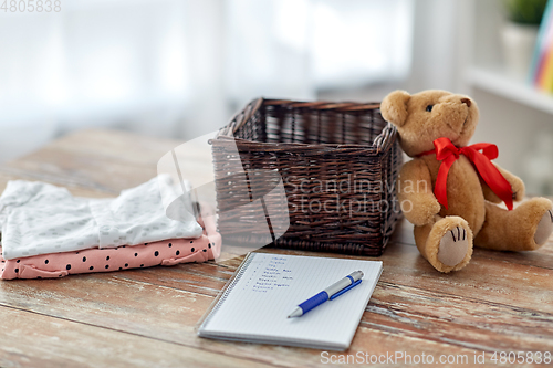 Image of baby clothes, teddy bear, toy blocks and notebook