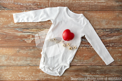 Image of baby bodysuit with red heart on wooden table