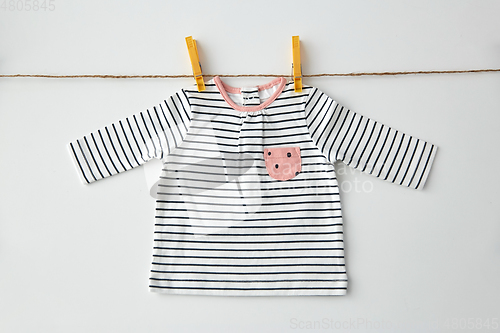 Image of shirt for baby girl hanging on rope with pins