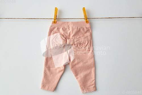 Image of pink pants for baby girl on clothesline with pins