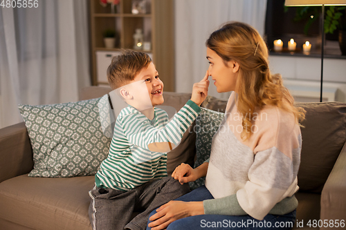 Image of happy mother touching little son's nose at home