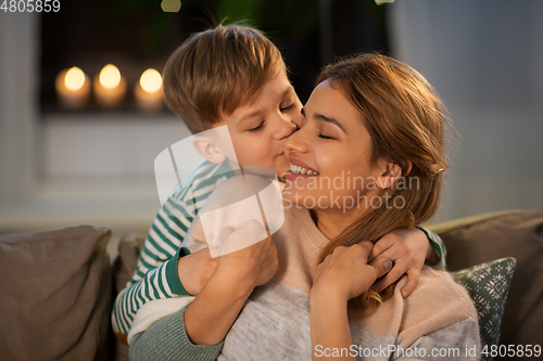 Image of happy mother and son hugging and kissing at home