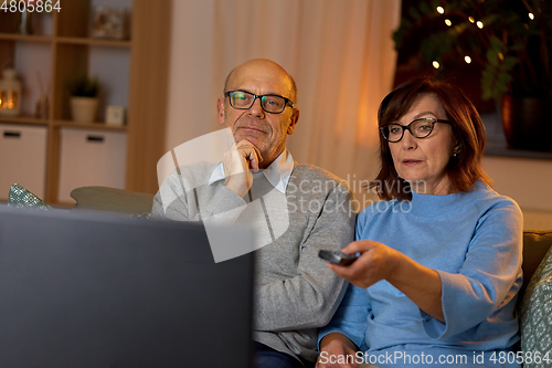 Image of senior couple watching tv at home in evening
