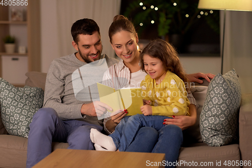 Image of happy family reading book at home at night