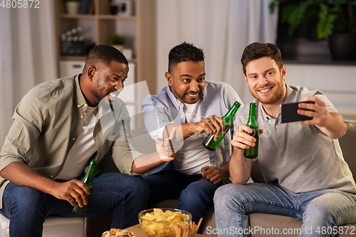 Image of male friends with smartphone taking selfie at home