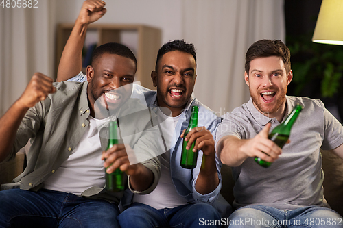 Image of happy male friends or fans drinking beer at home