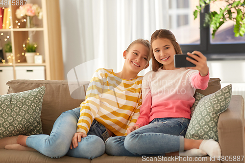 Image of happy girls taking selfie with smartphone at home