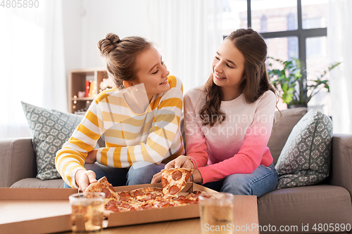 Image of happy teenage girls eating takeaway pizza at home