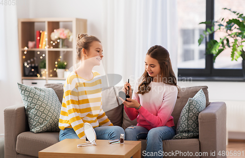Image of happy teenage girls doing make up at home