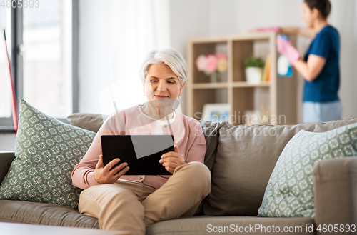 Image of old woman with tablet pc and housekeeper at home